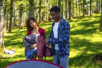 Two young campers collaborate, setting up their tent amidst a lush forest, enjoying the adventure