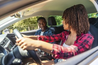 Young woman learning to drive, receiving guidance from her instructor as they navigate the car on a