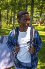 Young hiker wearing backpack exploring forest near campsite, enjoying outdoor adventure and