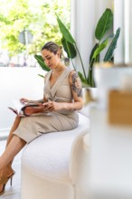 Young woman reading a magazine while waiting in a beauty salon, enjoying the relaxing atmosphere