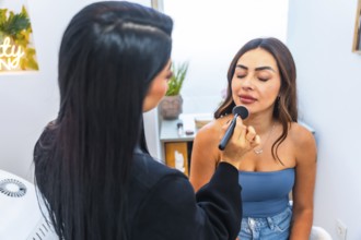 Beautician applying makeup on a client's face using a brush, enhancing her beauty in a professional