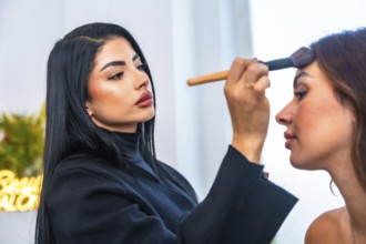 Makeup artist skillfully applying foundation on a client's face in a beauty salon, using a brush