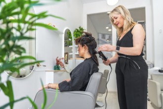Professional hairdresser styling a client's hair using a curling iron in a modern and bright salon