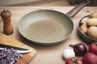 Fresh ingredients including potatoes, garlic, tomatoes, and onions are arranged on a wooden table