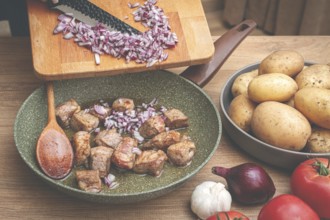 Adding chopped onion to the pan with meat, close-up
