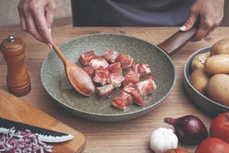 Diced pork meat, with vegetables, on a wooden kitchen table, in a cozy home environment