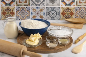 Baking ingredients, flour, butter, spices on wooden board in kitchen, with decorative tiles in