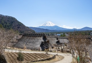 Iyashinosato open-air museum, old Japanese village with traditional houses, at the back volcano Mt.