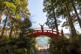 Young man walking on red bridge, path along Lake Ashi to Hakone shrine, Hakone, Japan