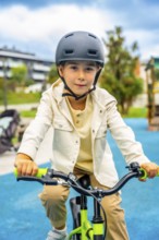 Young boy wearing a helmet rides a bicycle in a park, enjoying a sunny day outdoors while promoting