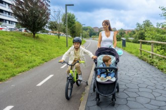Mother enjoying quality time with her two sons in a serene urban park, one riding a bicycle with
