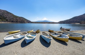 Rowing boats on shore, view across the lake to Mt Fuji volcano, Motosu Lake, Yamanashi Prefecture,