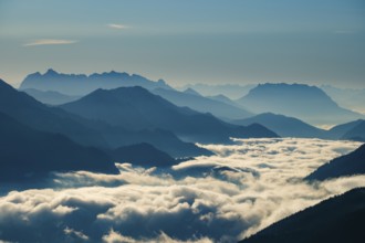 Blue-colored silhouette of mountains, fog in the valley, Wilder Kaiser and Chiemgau Alps, Upper
