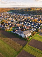 Aerial view of a village with adjacent fields surrounded by autumn colors, Aidlingen, Böblingen