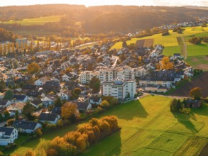 Settlement in autumn landscape with golden light over green fields and hills, Aidlingen, Böblingen