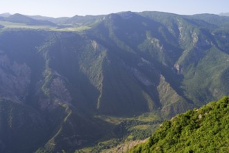 Green, wooded mountain slopes in the sun surrounding vast valleys, view of the Vorotan River