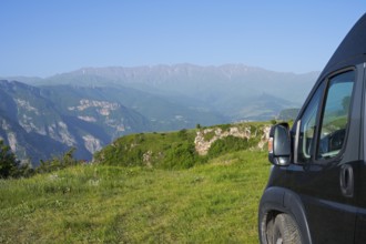 A van stands on a hill with a wide view of a green mountain landscape, camper near Halidzor, Syunik