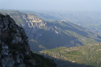 Wide view of rocky gorges and green slopes under a blue sky, view of the Vorotan River valley,