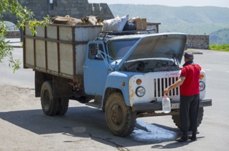 Man repairs a blue truck on a scenic road, GAZ-53 loaded with cows, Goris, Syunik province, Syunik,