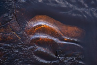Detail, orange-brown glowing stone in a stream, forest, near Sunne, Sweden