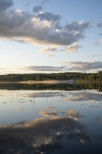 Clouds reflected on the water surface, forest lake, evening mood, at Sunne, Sweden