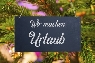 (Photo montage) Company holidays at Christmas: sign with the inscription WIR MACHEN URLAUB in front