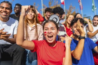 Diverse young people cheering excitedly at a stadium, wearing team colors and face paint while