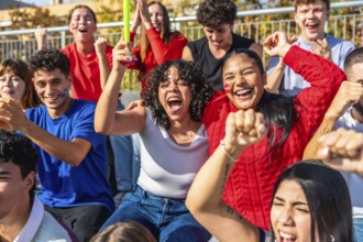 Diverse group of enthusiastic young people celebrating their team's victory at a stadium, waving