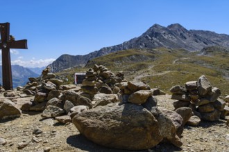Stone men in front of an alpine landscape at the Timmelsjoch rest house on the border between