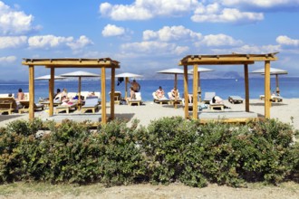 Parasol, sun lounger, sea, pebble beach, piled up with sand, people on the beach, behind Turkish