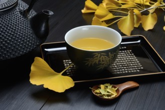 Ginkgo tea in tea bowl and ginkgo leaf, tea leaves in a spoon, ginkgo biloba