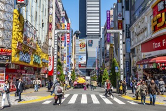 Bustling street scene in Japan with modern buildings and colorful billboards, figure of Godzilla