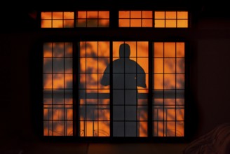 Shadows of a man in kimono, on the balcony behind sliding shoji doors in a traditional Japanese