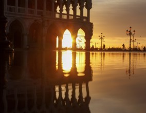 View through the arcades of the Doge's Palace at sunrise on Piazzetta during Acqua Alta, Venice,