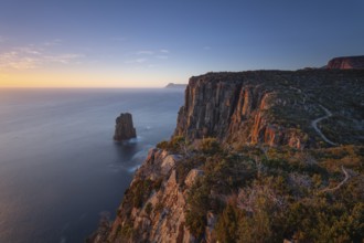 Long exposure at sunrise shows glowing dawn over the dramatic cliffs of Cape Hauy. View towards