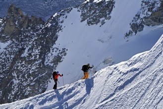 Two mountaineers run across a snow-covered mountain ridge, Aiguille du Midi, Chamonix-Mont-Blanc,