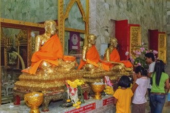 Buddhist believers Buddhists pray making offerings to statues of Buddhist monks covered with gold