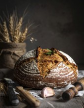 Rustic loaf of whole grain bread, fresh baked, close up of bread on dark wooden table, golden rust,
