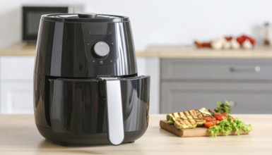 Air fryer with grilled vegetables, wooden table in the kitchen, healthy eating, healthy vegetarian