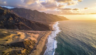 Desert landscape converges with ocean along a rugged coastal area, shore break at cliffs, blue