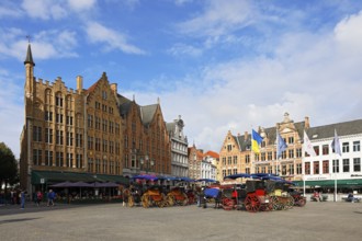 Historic houses on the market square in the old town of Bruges with horse-drawn carriages, Grote