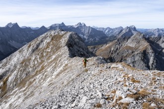 Hikers on the summit ridge of the Gamsjoch, behind rock faces of the Laliderer Spitze, eastern