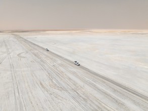 Aerial view, two off-road cars driving on a salt pan, arid landscape, Botswana