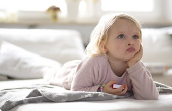 Child, girl, 4 years, blonde, lying on sofa, watching TV, watching television, watching television,