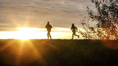 Woman and child walk across a dike on the island of Fehmarn at sunset, 13.10.2025, Fehmarn,