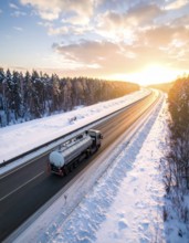 Petrol cargo truck lorry tanker driving on highway hauling oil products at sunrise, wide snowy