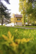 Small yellow house in a meadow surrounded by trees in autumn colors, Überlingen, Lake Constance,