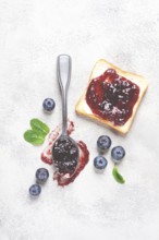 A spoon with blueberry jam, on a white table, breakfast, top view, homemade, no people