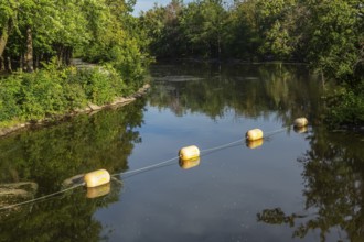 String of yellow cautionary navigation marker buoys on water surafce of river serving to warn,