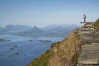 Woman with walking sticks standing on a ledge, Rørsethornet stone stairs, with 3292 steps one of